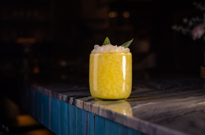 An elegant yellow cocktail topped with mint and crushed ice, served at Loreto.