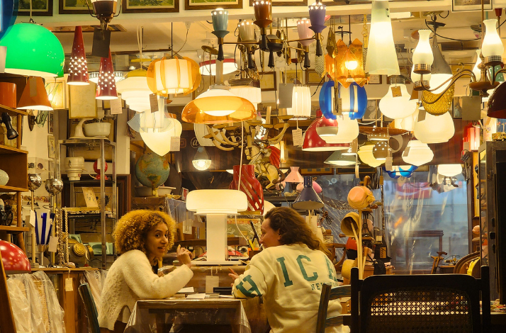 People enjoying drinks at a bar filled with lamps.