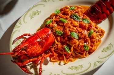 Lobster fra diavolo with spaghetti in rich tomato sauce, garnished with fresh basil leaves, served at Opto.