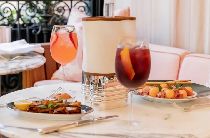 Two fruit-garnished cocktails and light bites arranged on a marble dining table at Casa Cruz New York.