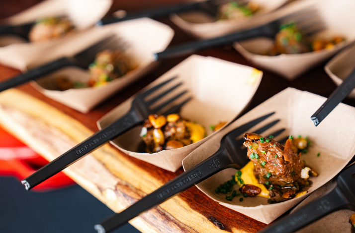 Rows of small cardboard trays holding grilled meat with some fresh sides, served at Austin Food and Wine Festival.
