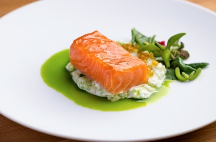 Glazed salmon fillet set on creamy herb base with bright green sauce, and golden roe at Jacaranda.