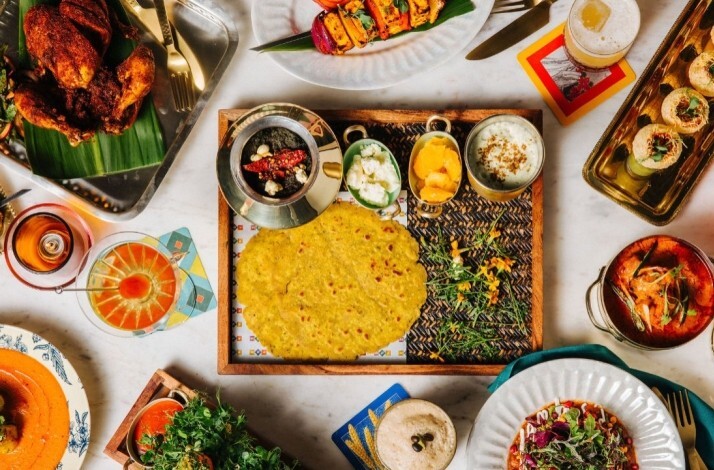Vibrant Indian spread displayed from above, showcasing flatbread, shrimp curry, grilled paneer, chutneys, and drinks.