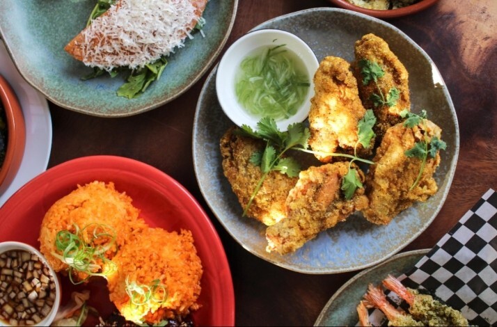 verhead view of crispy fried chicken with herbs, orange rice, and dipping sauces served at Prubechu.