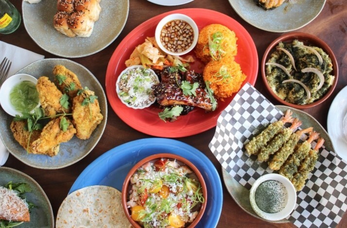 Overhead view of crispy fried chicken with herbs, orange rice, and dipping sauces served at Prubechu.