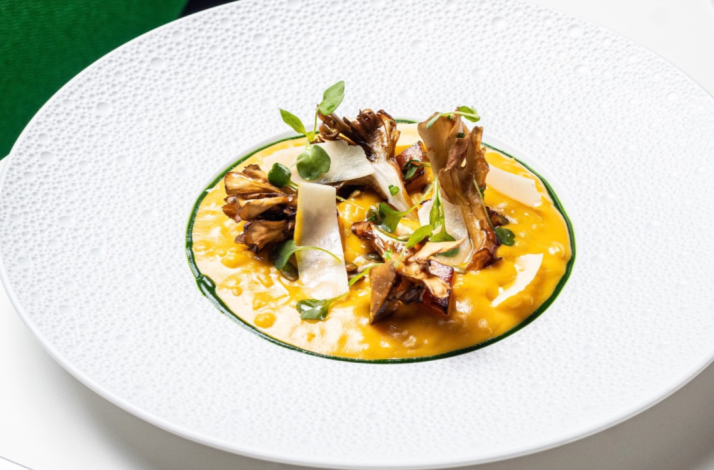 Golden risotto topped with roasted maitake mushrooms, shaved cheese, and microgreens at Le Jardinier Miami.
