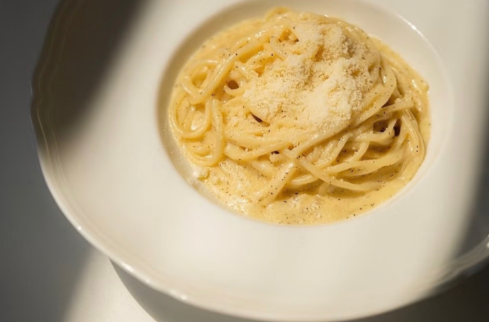 Plate of Cacio e Pepe, featuring a mound of spaghetti coated in a creamy cheese and black pepper sauce.