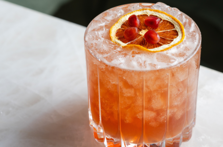 Iced citrus cocktail with a dried orange wheel and pomegranate arils at Le Jardinier Houston.