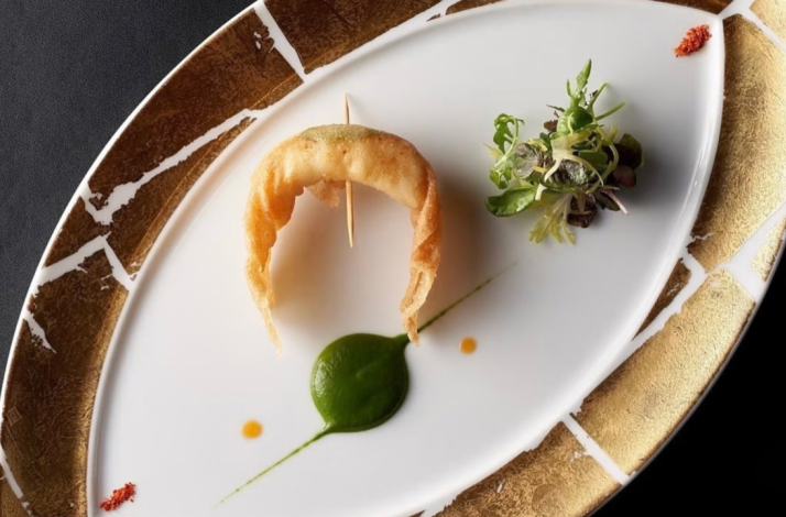 Delicate shrimp appetizer on an oval plate with green purée and microgreens, styled with clean, modern plating.