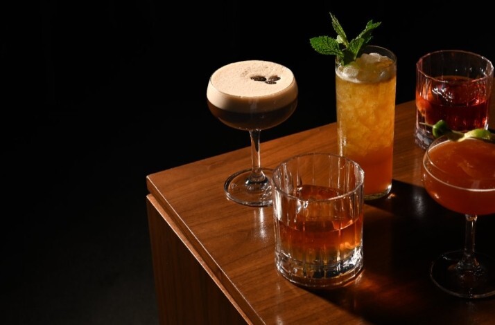 A selection of handcrafted cocktails served at Trade on a wooden table.
