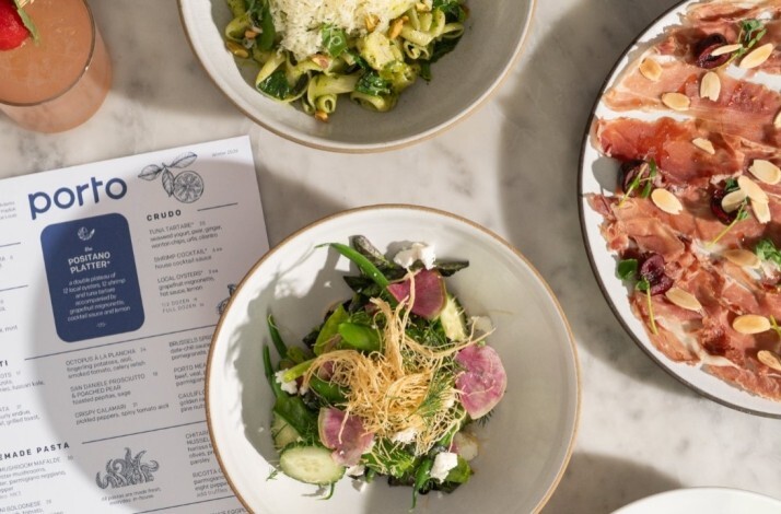 Porto Boston's Winter 2026 menu alongside shared plates including green pasta, a salad, prosciutto, and a pink cocktail.
