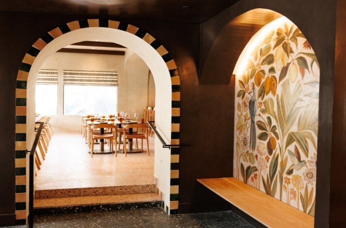 Arched entryway leading into a bright dining room with warm wood tables and chairs at Maria Isabel.