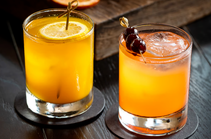 Vibrant signature cocktails garnished with citrus and cherries.