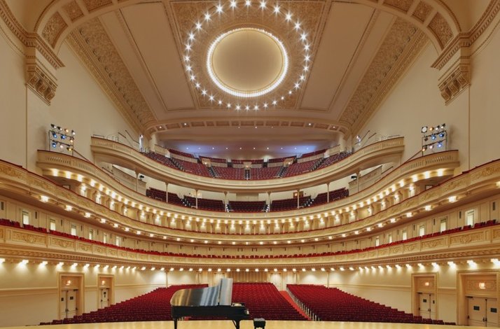 An empty concert hall with a piano on the stage at Carnegie Hall.