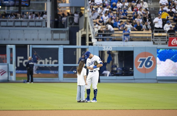 Baseball player with a kid on the field.