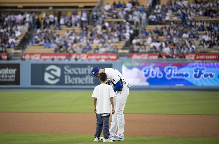 Baseball player with a kid on the field.