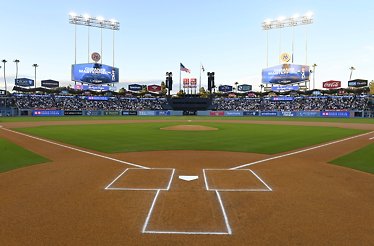 Dodger Stadium's field-level view from home plate, featuring the infield diamond, outfield scoreboard, and surrounding sponsor signage.