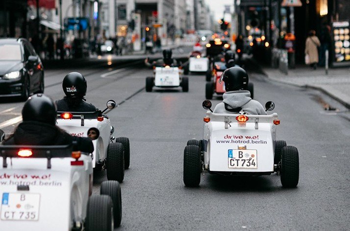 A view from behind of men riding in HotRod cars.
