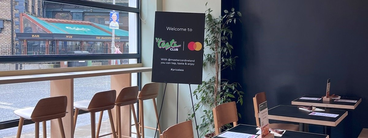 Dining area of Nomo Ramen with a welcome sign with Taste of Dublin and Mastercard logos on it