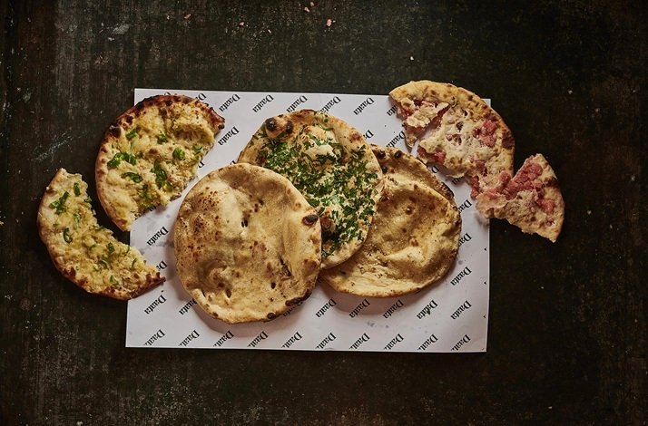 Assorted flatbreads including herb and meat-topped varieties on Daata-branded paper at DAATA, Sandymount.