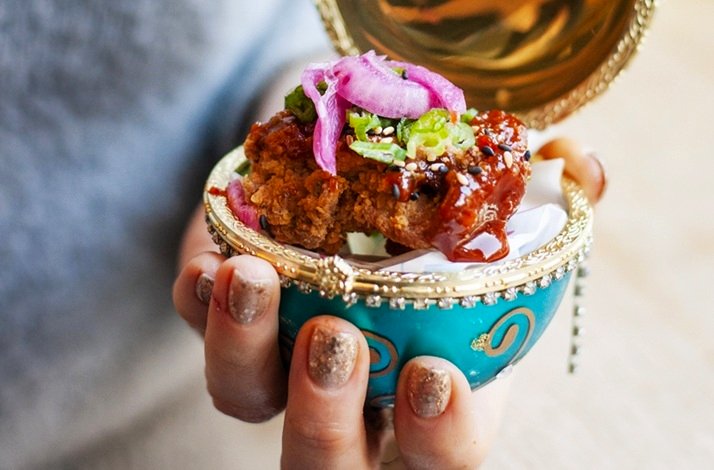 A person holding a small container filled with food, showcasing a casual dining moment.