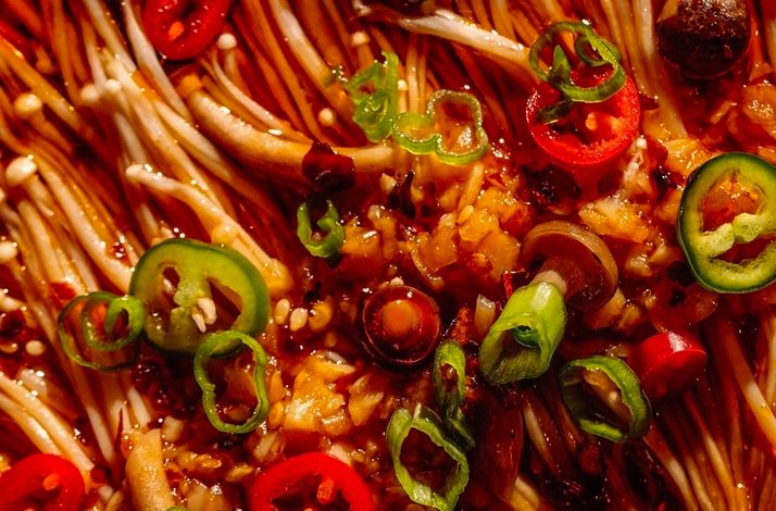 Enoki mushrooms in a spicy red sauce with chili peppers and scallions.