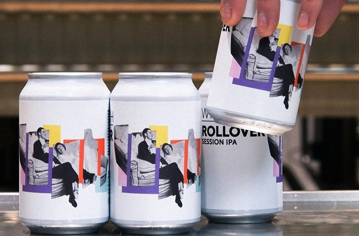 A person holds several cans of beer on a table, showcasing a casual gathering or celebration atmosphere.