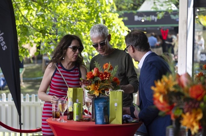 People at a table with drinks and flowers at Taste of Dublin festival, Merrion Square.