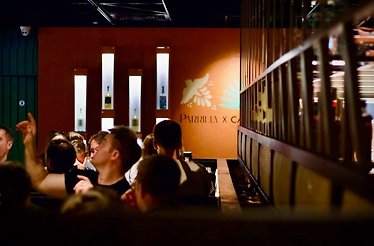 An inside view Parrilla Ranelagh filled with guests and bottles displayed on the wall 