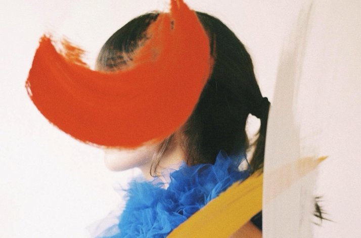 Photo of Coco Dávez in bright colors with her face hidden in red.