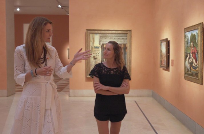 Andrea Velasco gesturing toward Renaissance artwork while guiding Susana Rubio at the Thyssen Museum.