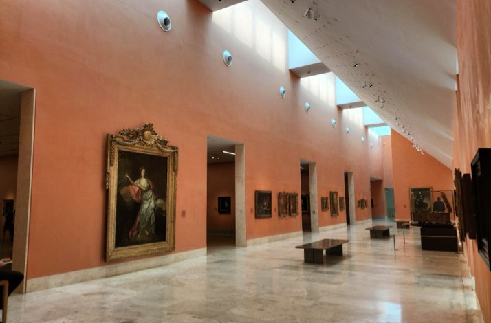 A gallery hall at the Thyssen-Bornemisza National Museum, featuring paintings and soft lighting.