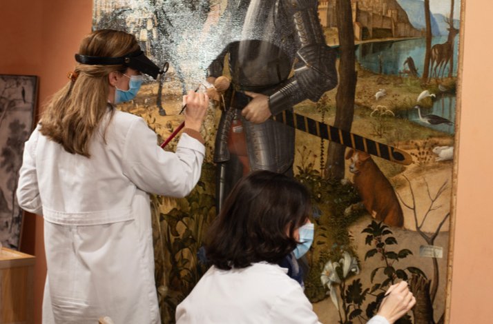 Restorers are restoring the painting Young Knight in a Landscape by Vittore Carpaccio.