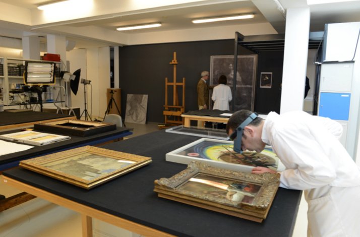 A restorer takes a close look at a painting in the Thyssen Museum.