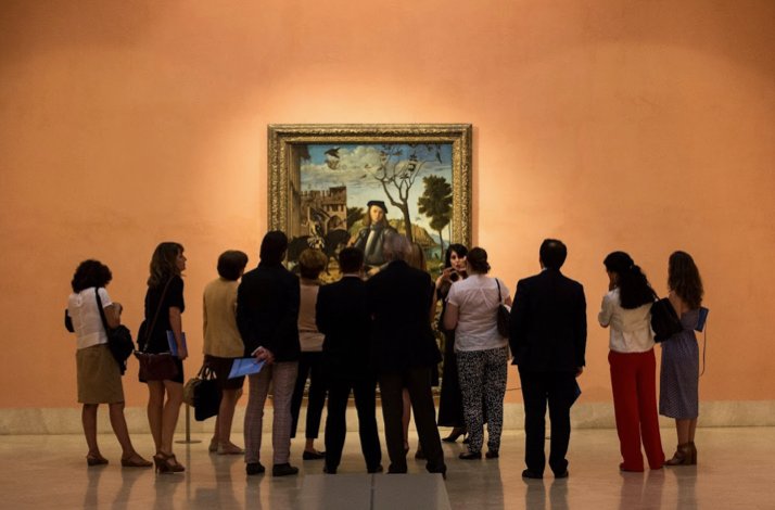 People look at Young Knight in a Landscape by Vittore Carpaccio at the Thyssen Museum.