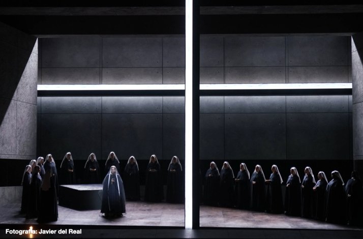 A chorus of people in dark robes on the stage of Teatro Real. Photo by Javier del Real.