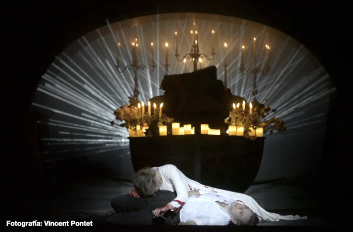 Romeo and Juliette lie in a final, blood-stained embrace on a dark stage. Photo by Vincent Pontet