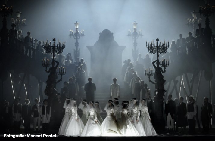 Brides in white gowns dance before a grand staircase shrouded in mist and cold light in Romeo and Juliette. Photo by Vincent Pontet