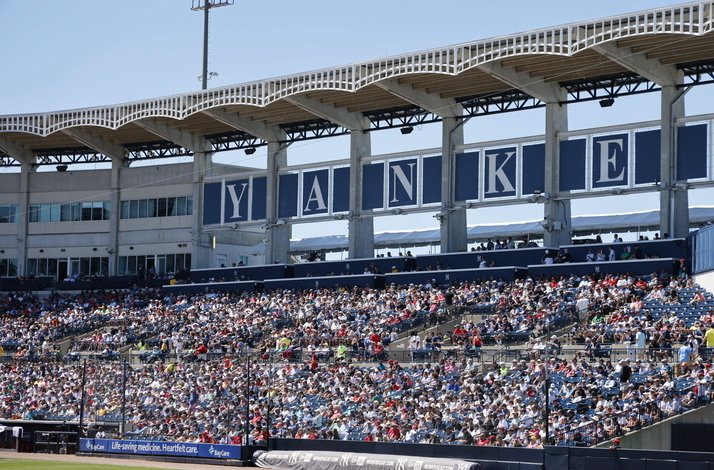 Spectators enjoy a baseball game at Yankee Stadium, with clear skies and a lively atmosphere.