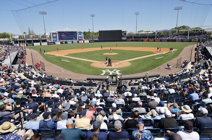 View from behind home plate at Yankee Stadium, with a game in progress and a packed crowd.