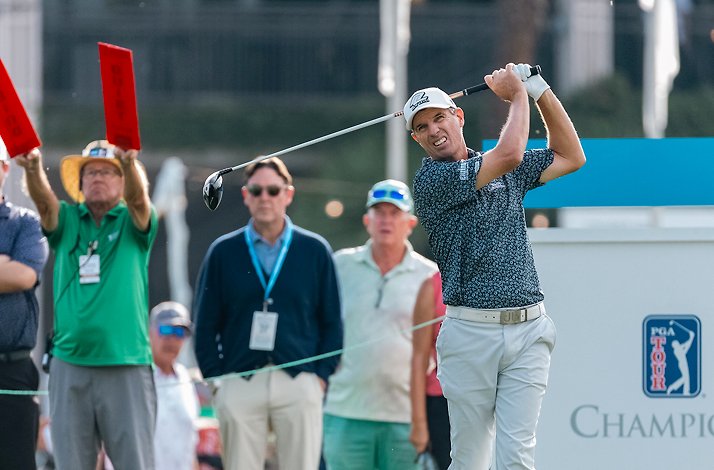 A golfer swinging a driver at the Charles Schwab Cup Championship with spectators watching.