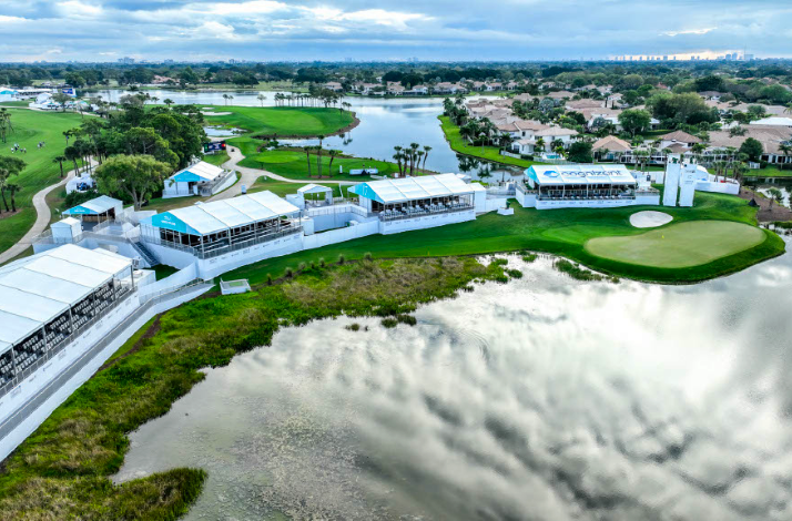 Aerial view of a golf course with lakes and event structures beside the green