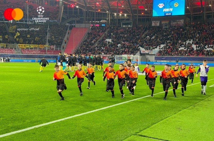 Children in football uniforms running on a stadium at Stade de Roudourou.