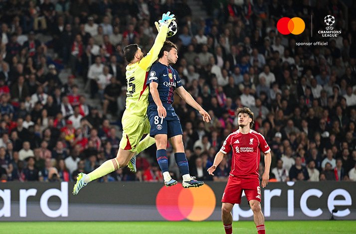 PSG goalkeeper punching ball away from number 87 during aerial challenge vs Liverpool in Champions League.