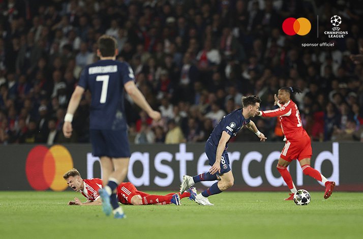 PSG midfielder dribbling past fallen Bayern player with Fabian Ruiz visible in background during Champions League semi-final.