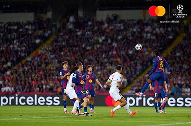 PSG player heading ball under pressure from Barcelona defenders during Champions League league phase match.