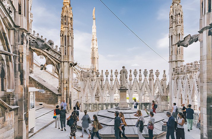 People walk around the Duomo di Milano and take in the sights.