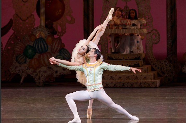 Dancers performing a duet in NYCB's The Nutcracker on a festive stage.