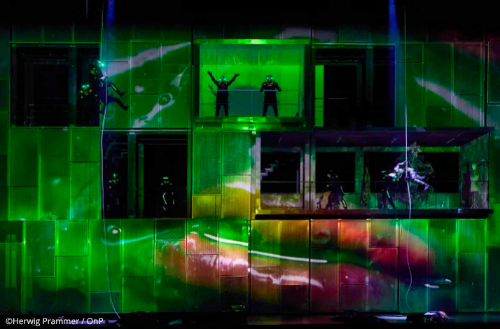 Silhouetted cast members spread across a glowing green multi-tiered set during Calixto Bieito's The Valkyrie at Opera Bastille.. © Herwig Prammer / OnP.