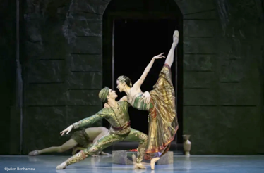 A male and female ballet dancer perform a passionate duet from La Bayadère on a theatrical stage.